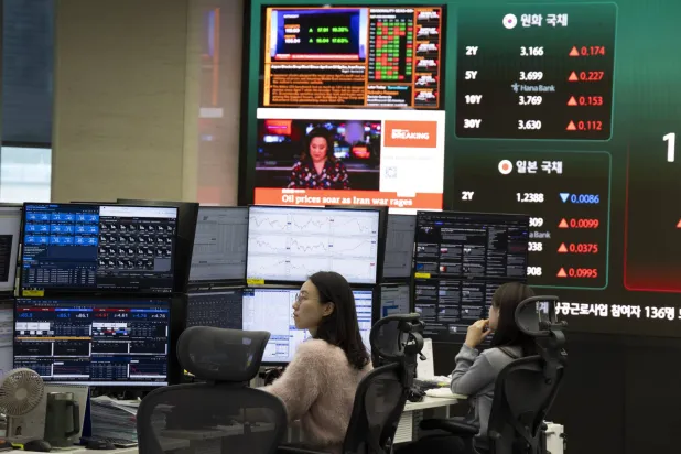 متداولون كوريون جنوبيون يعملون أمام شاشات تعرض مؤشرات الأسهم ببنك «هانا» في سيول (إ.ب.أ)