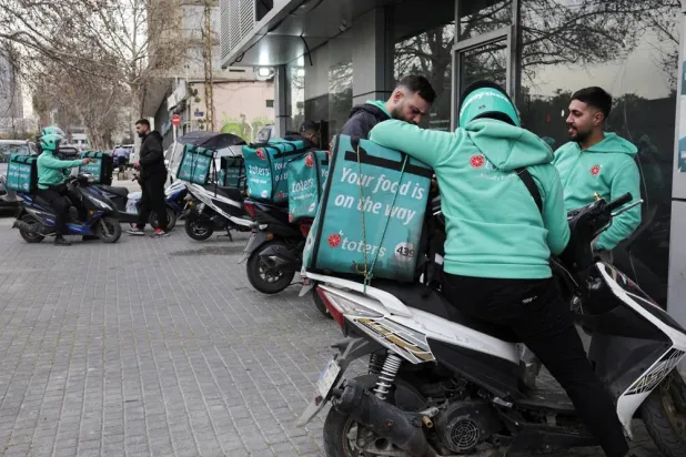  People who work as delivery drivers for the Toters delivery app stand outside a delivery center in Beirut, Lebanon, March 18, 2026. (Reuters)