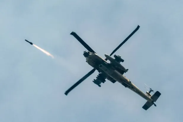 İsrail Hava Kuvvetlerine ait bir AH-64 Apache saldırı helikopteri, 18 Mart 2026'da kuzey İsrail ile güney Lübnan arasındaki sınır boyunca uçarken füze ateşliyor (AFP)