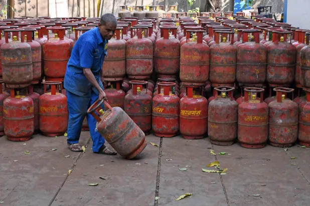 عامل ينقل أسطوانة غاز البترول المسال مملوءة من مستودع في مومباي (د.ب.أ)