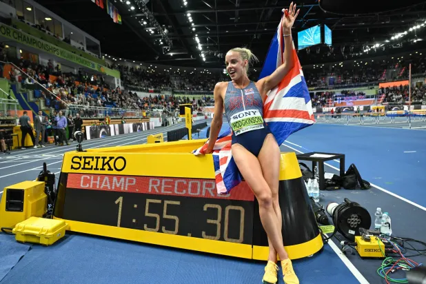 العداءة البريطانية كيلي هودجكينسون تحتفل بلقبها العالمي الأول داخل قاعة (إ.ب.أ)