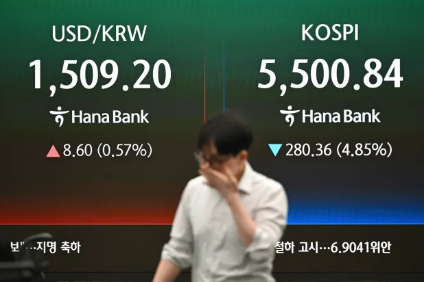 أحد تجار العملات يمر أمام شاشة تعرض مؤشر بورصة كوريا الجنوبية (كوسبي) وسعر صرف الوون الكوري مقابل الدولار الأميركي (أ.ف.ب) 