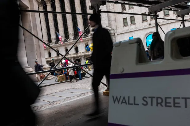 يسير أشخاص في الحي المالي حيث مقر بورصة نيويورك في مانهاتن (أ.ف.ب)