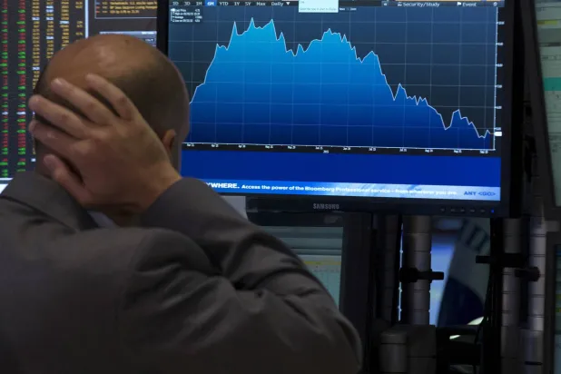 أحد المتخصصين في التداول يراقب شاشة داخل بورصة نيويورك (رويترز)