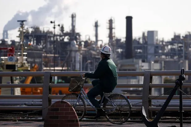 فني يسير بجوار إحدى مصافي النفط اليابانية (رويترز)