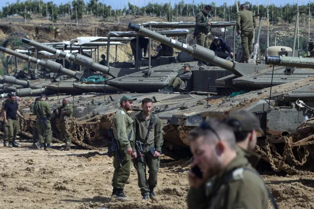 Israeli soldiers stand next to tanks near the Israeli side of the border with Lebanon, March 23, 2026. REUTERS/Tyrone Siu