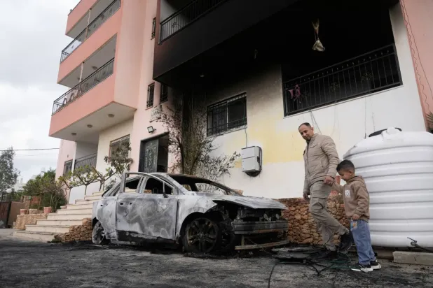 İsrailli yerleşimcilerin Batı Şeria'nın Nablus kenti yakınlarındaki köylere düzenlediği saldırının ardından dün yanmış bir aracı inceleyen Filistinliler (AP)