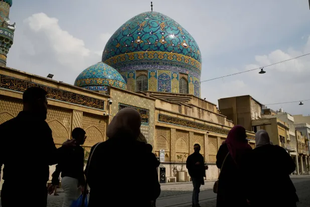 يمر الناس أمام مسجد حيدر خانة في شارع رشيد بوسط مدينة بغداد (أ.ب) 