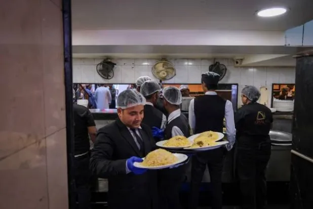 نادل يحمل طبق برياني لتقديمه للزبائن داخل مطعم في كولكاتا بالهند (رويترز)