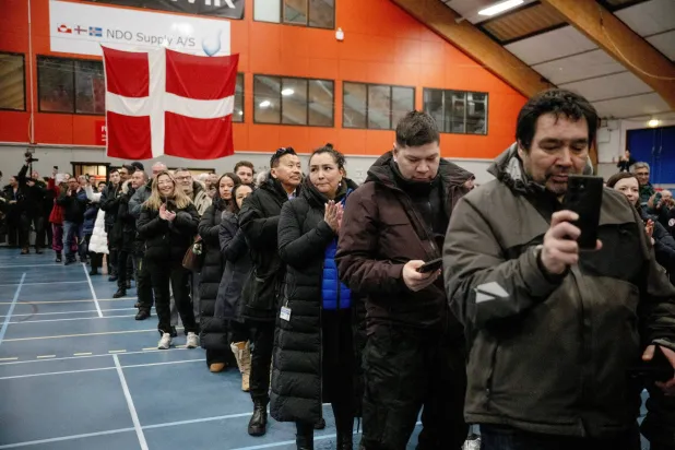 أشخاص يقفون داخل مركز اقتراع في نوك بغرينلاند (رويترز)