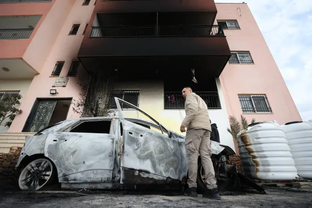 فلسطينيون يتفقدون الأضرار في قرية دير الحطب بالضفة الغربية بعد هجوم مستوطنين (إ.ب.أ)