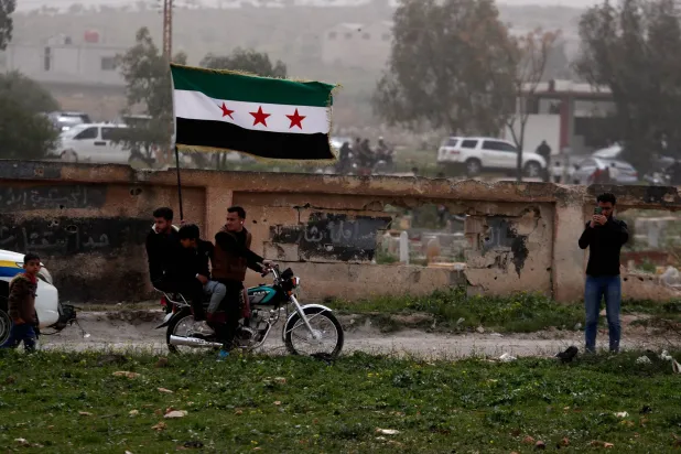 Demonstrators carry a Syrian flag during a rally commemorating the15th anniversary of the Syrian uprising against the Bashar al-Assad regime in Daraa, southern Syria, Wednesday, March 18, 2026. (AP)
