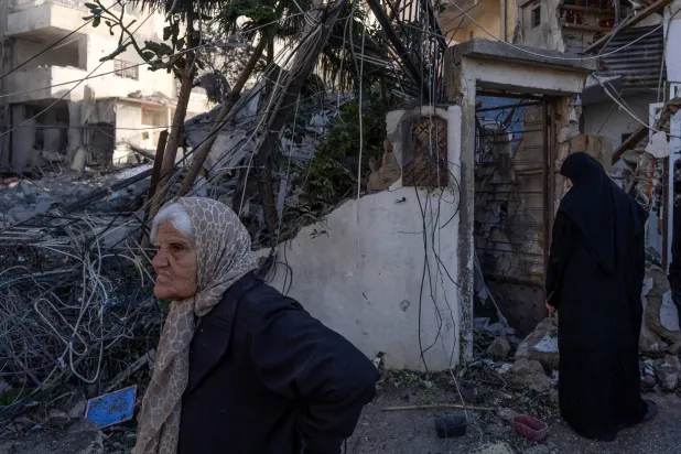 Women stand next to a building destroyed by an Israeli strike in Tyre, Lebanon, March 24, 2026. REUTERS/Manu Brabo