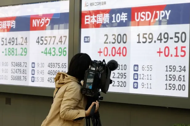 Tokyo’da Japon devlet tahvillerinin 10 yıllık getirisini gösteren gösterge panolarını kayda alan bir kameraman (EPA)