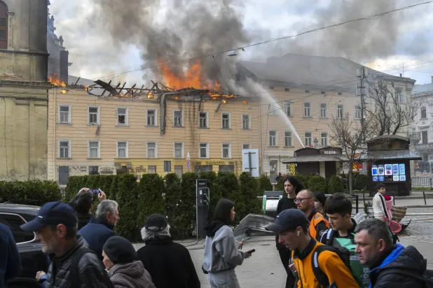 أوكرانيون يتجمعون أمام الكنيسة التاريخية بمدينة لفيف غرب أوكرانيا خلال عمليات إطفاء الحرائق بعد استهدافها بهجوم روسي يوم 24 مارس 2026 (إ.ب.أ)