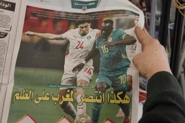 رجل يقرأ صحيفة مغربية بعد صدور قرار تجريد السنغال من اللقب الأفريقي (أ.ف.ب)