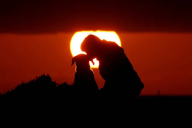 FILE PHOTO: A woman gives her dog a kiss as they watch the sunset at Anchor Bay outside Mellieha, Malta, January 26, 2018.  REUTERS/Darrin Zammit Lupi/File Photo