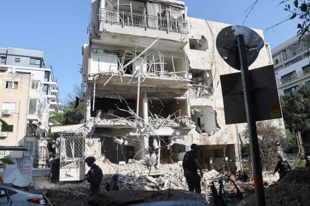 أفراد من فرق الإنقاذ الإسرائيلية في موقع الهجوم الصاروخي الإيراني في تل أبيب (أ.ف.ب)