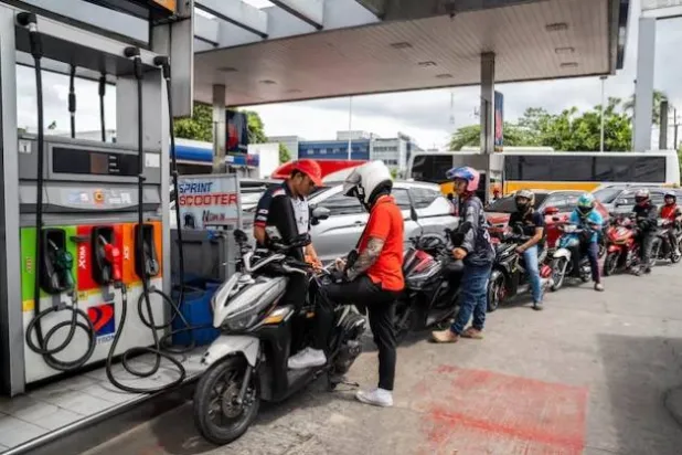 عامل يملأ دراجة نارية بالوقود في محطة بكويزون سيتي الفلبين (رويترز)