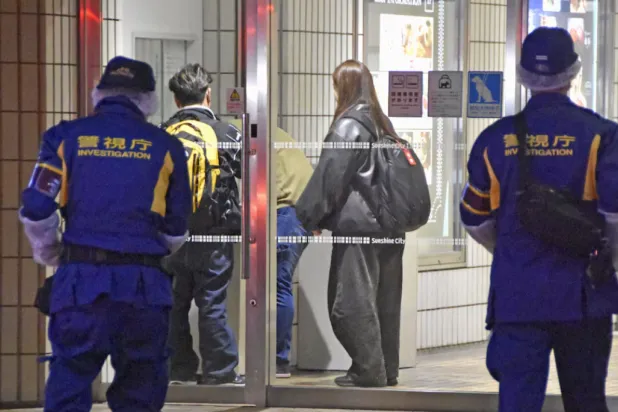 Police officers walk toward a commercial complex to investigate where a female employee at a Pokemon merchandise shop was stabbed to death at Ikebukuro district in Tokyo, Japan March 26, 2026, in this photo taken by Kyodo. Mandatory credit Kyodo/via REUTERS
