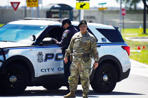 شرطي أميركي وأحد عناصر القوات الجوية بدورية بعد العثور على جسم مشبوه قرب قاعدة ماكديل في تامبا بولاية فلوريدا الأميركية 18 مارس 2026 (رويترز)