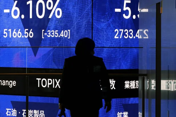 رجل يمر أمام شاشة تعرض حركة الأسهم في العاصمة اليابانية طوكيو (إ.ب.أ)