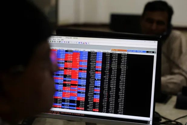 وسطاء يتداولون على مكاتبهم داخل شركة وساطة في مومباي (رويترز)