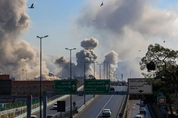  Motorists drive along an expressway as plumes of smoke rise after a strike in Tehran on March 5, 2026.  (Photo by ATTA KENARE / AFP)