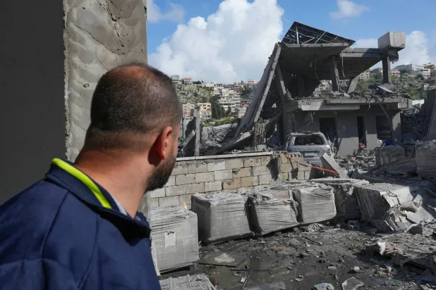 A man checks a destroyed house that was hit in an Israeli airstrike in Saksakiyeh village, south Lebanon, Friday, March 27, 2026. (AP Photo/Hussein Malla)