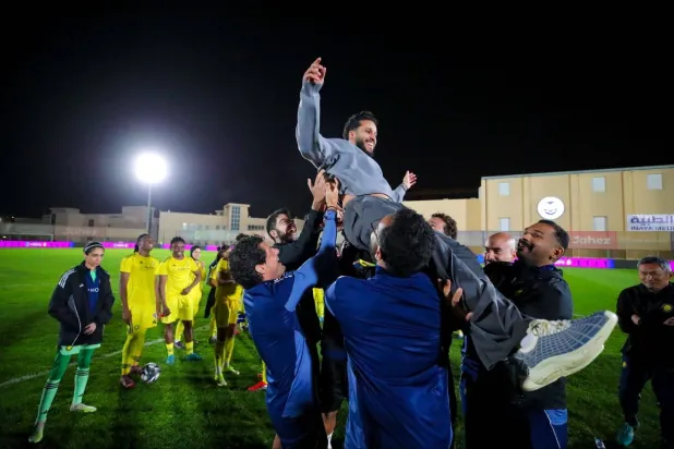 العلوني محتفلاً مع الجهاز الفني باللقب (نادي النصر)