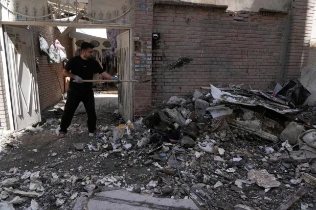  A man clears debris from a building damaged after a nearby residential building was hit in a US-Israeli strike in Tehran, Friday, March 27, 2026. (AP) 