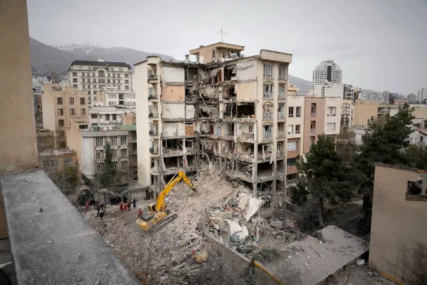 Iranian Red Crescent emergency workers use a bulldozer to clear rubble from a residential building that was hit in an earlier U.S.-Israeli strike in Tehran, Iran, Monday, March 23, 2026. (AP Photo/Vahid Salemi)