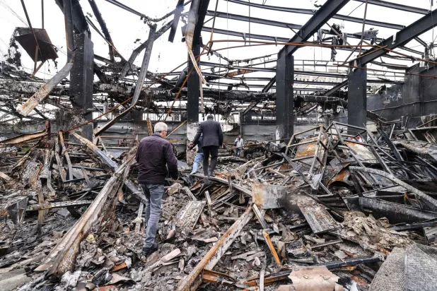 Iranian officials and journalists make their way through debris at car service center in eastern Tehran that was hit by a missile strike, on March 28, 2026. (Photo by ATTA KENARE / AFP) / 