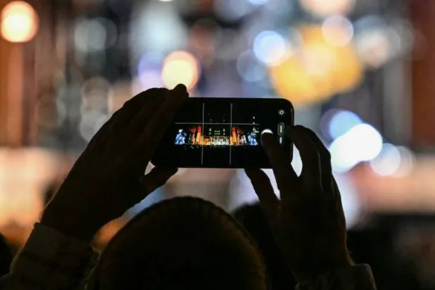 A fan takes photos at an event in London to mark the 50th birthday of US tech giant Apple. JUSTIN TALLIS / AFP

