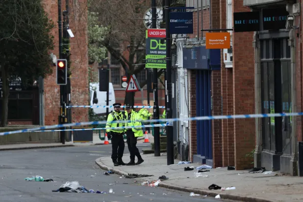 Police officers work near to a variety of personal items seen covering the road inside a cordon set up on Friar Gate in central Derby, central England on March 29, 2026, following an incident the night before where was vehicle has driven into pedestrians. (Photo by Darren Staples / AFP)
