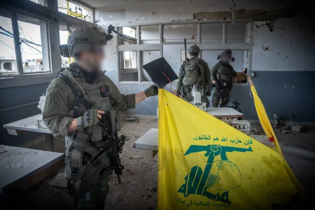 جندي إسرائيلي من وحدة «شيطيت 13» يمسك بعلم عليه شعار «حزب الله» خلال العمليات العسكرية في جنوب لبنان الجيش الإسرائيلي)