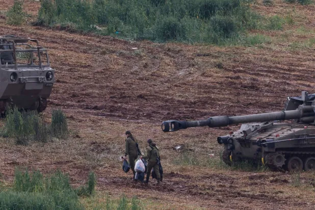 Israeli army soldiers walk next to a self-propelled Howitzer artillery gun positioned in the upper Galilee in northern Israel near the border with southern Lebanon on March 29, 2026. (AFP)