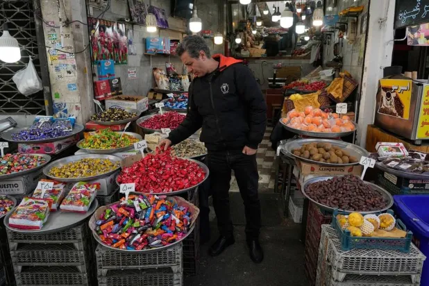  A shopkeeper arranges items at his shop around the traditional grand bazaar of Tehran, Iran, Sunday, March 29, 2026. (AP) 