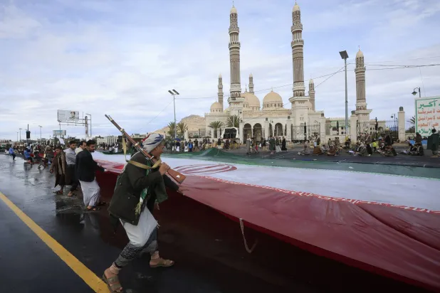 عناصر حوثية ترفع العلم الإيراني في صنعاء (إ.ب.أ)