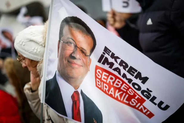 متظاهرون يرفعون لافتات تطالب بإطلاق سراح رئيس بلدية إسطنبول المحتجز أكرم إمام أوغلو مع انطلاق محاكمته بتهمة الفساد في قاعة داخل سجن سيليفري (أ.ف.ب)