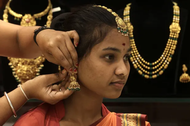An Indian woman tries on gold ornaments at a jewelry shop in Bangalore (EPA)