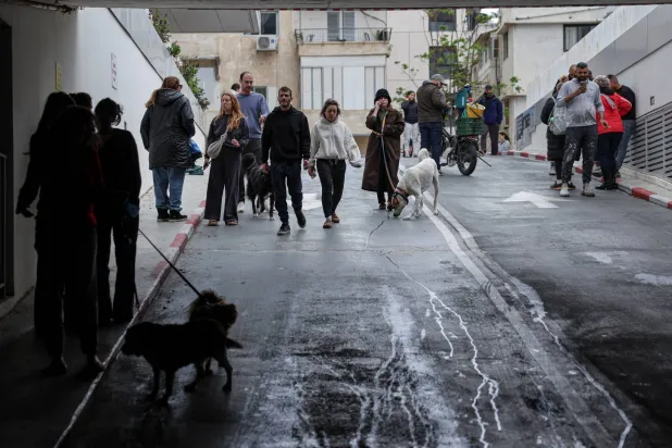 إسرائيليون يتوجهون نحو موقف سيارات تحت الأرض للاحتماء مع دوي صفارات الإنذار في تل أبيب (رويترز)