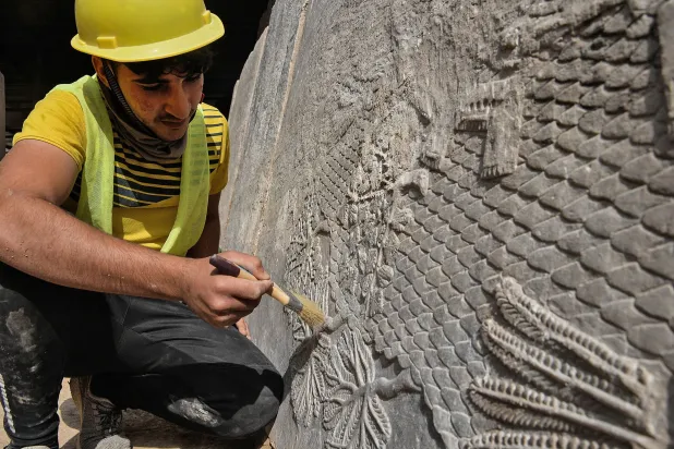 An Iraqi worker excavates a rock-carving relief recently found at the Mashki Gate, one of the monumental gates to the ancient Assyrian city of Nineveh, on the outskirts of what is today the northern Iraqi city of Mosul on October 19, 2022. (AFP)