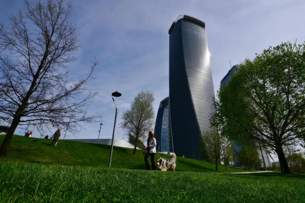 A woman walks her dog at the CityLife Shopping District in Milan, on March 25, 2026. (Photo by Stefano RELLANDINI / AFP)