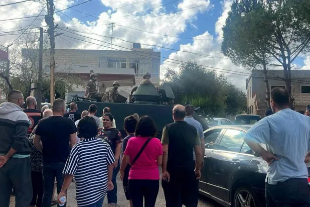 لبنانيون يتجمعون أمام دورية للجيش قرب دير في بلدة رميش بعدما غادروا قرية عين إبل يوم 1 أكتوبر 2024 خلال الحرب السابقة (رويترز)