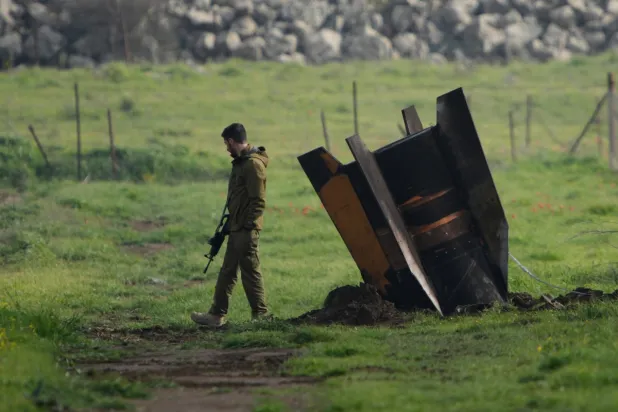  İsrail işgali altındaki Golan Tepeleri'nde açık bir alanda, İran'dan fırlatılan ve İsrail hava savunma sistemi tarafından engellenen bir füzenin yanında duran İsrail askeri, 19 Mart 2026 Perşembe
