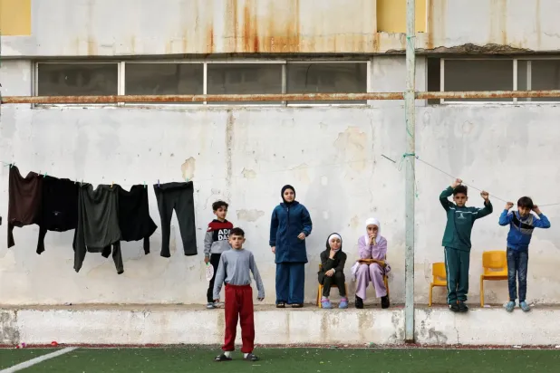 İsrail'in Lübnan'a yönelik saldırıları sırasında geçici sığınak olarak kullanılan ortaokulun bahçesinde bir grup yerinden edilmiş çocuk (Reuters)