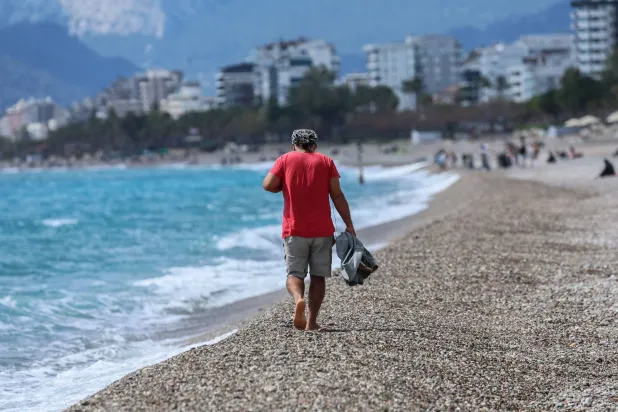 A man walks on Konyaalti beach during a sunny day in Antalya, southern Türkiye, on March 30, 2026. (Photo by Adem ALTAN / AFP)