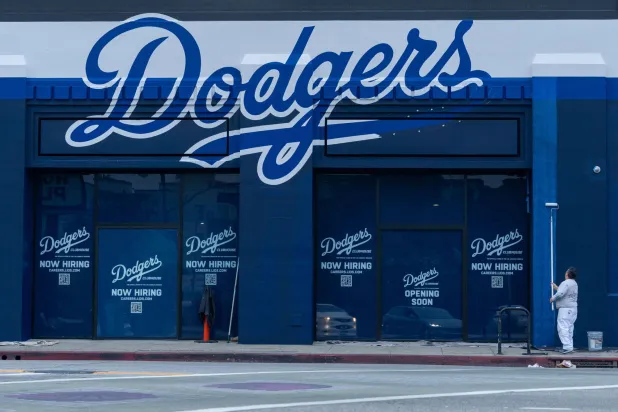 عامل يدهن الجدران الخارجية لمبنى يعرض وظائف لدى فريق «لوس أنجليس دودجرز» وسط مدينة لوس أنجليس (رويترز)