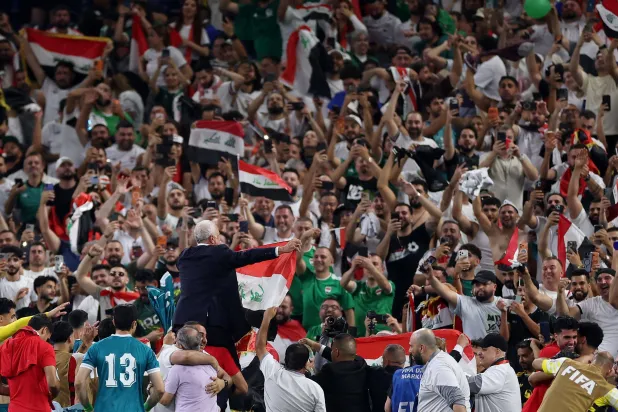 لاعبو العراق يحملون مدربهم على الأعناق بعد نهاية المباراة (أ.ف.ب)